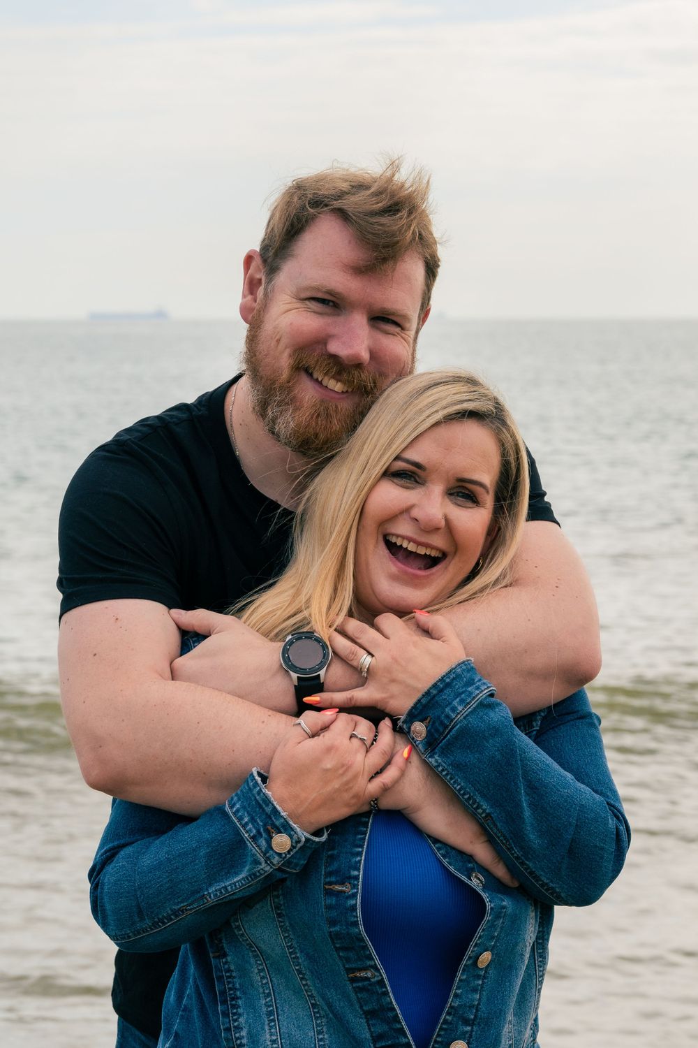 Happy couple sharing a joyful embrace by the seaside.