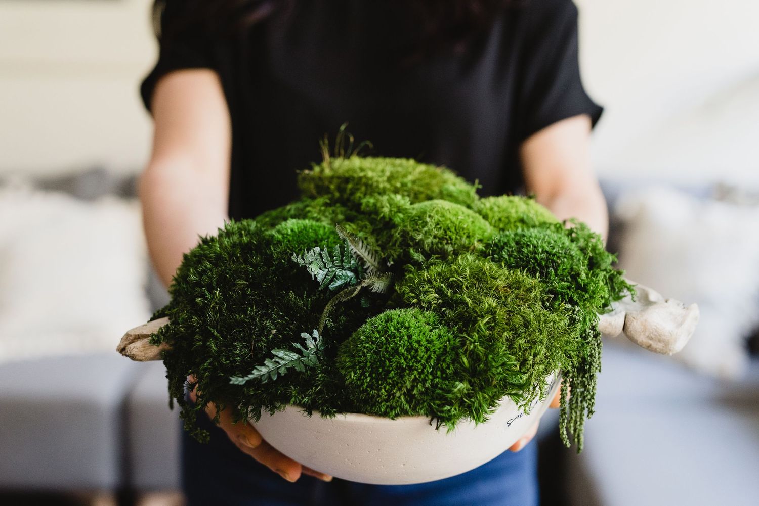 Close up of bowl of moss art in woman's hands.