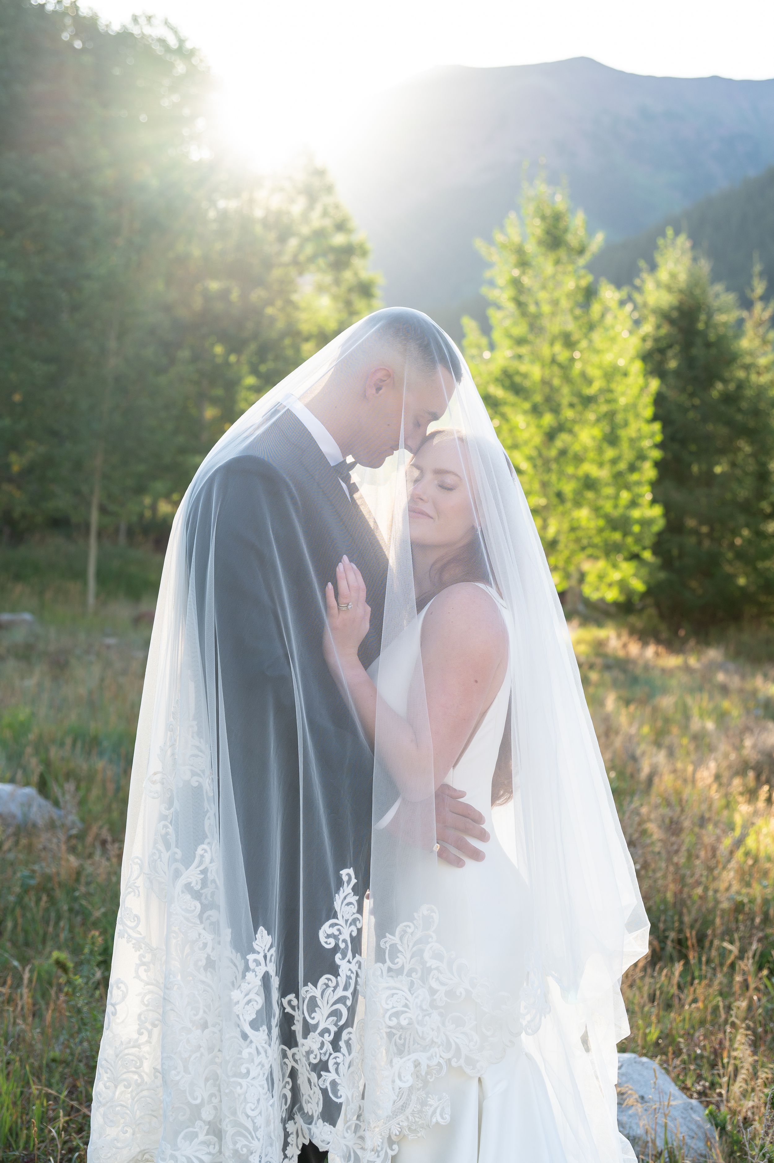Bride and groom share intimate moment under wedding veil at golden hour with mountain backdrop for Maroon Bells Sunrise Elopement