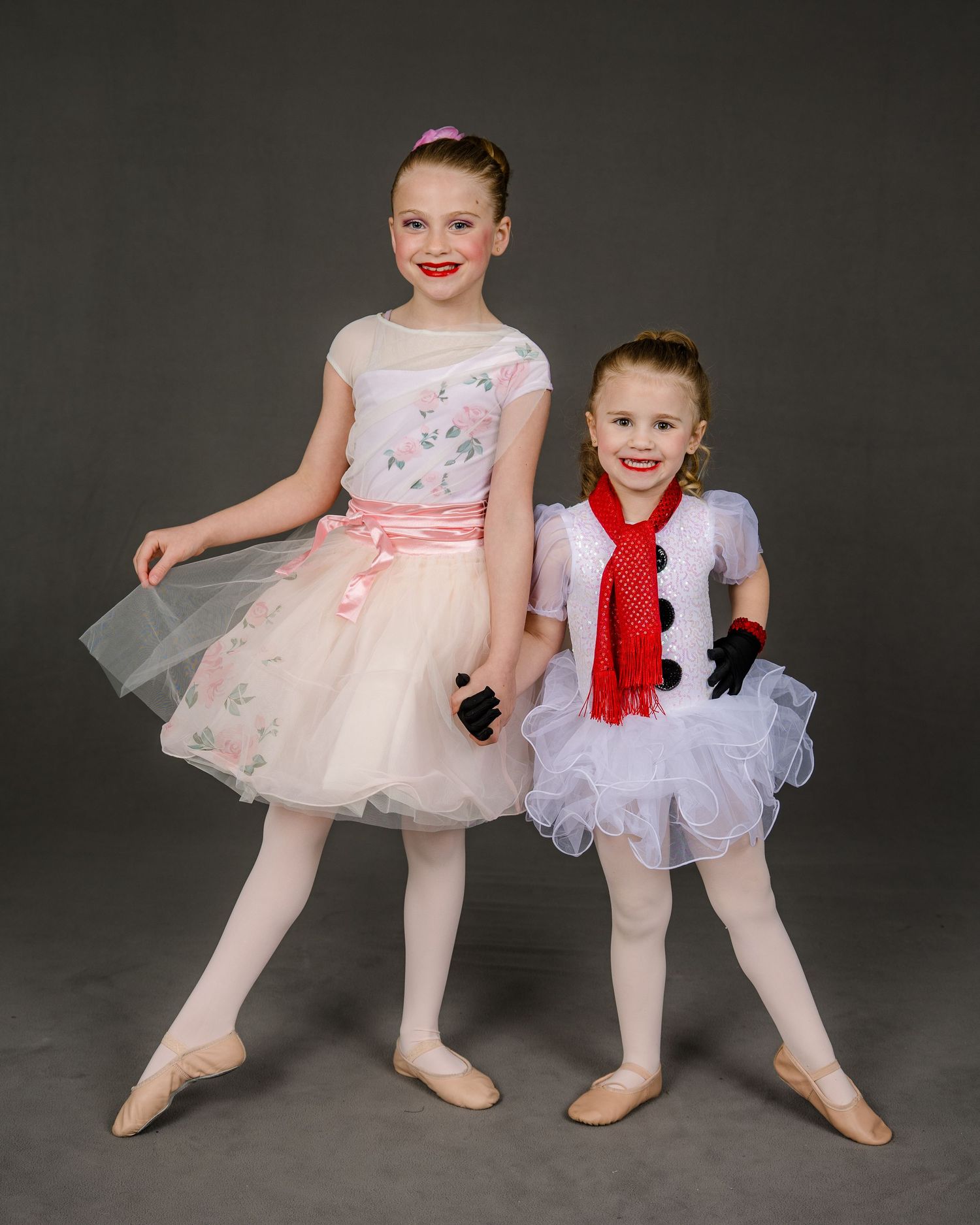 Two dancers in mint green and purple dresses share joyful embrace.