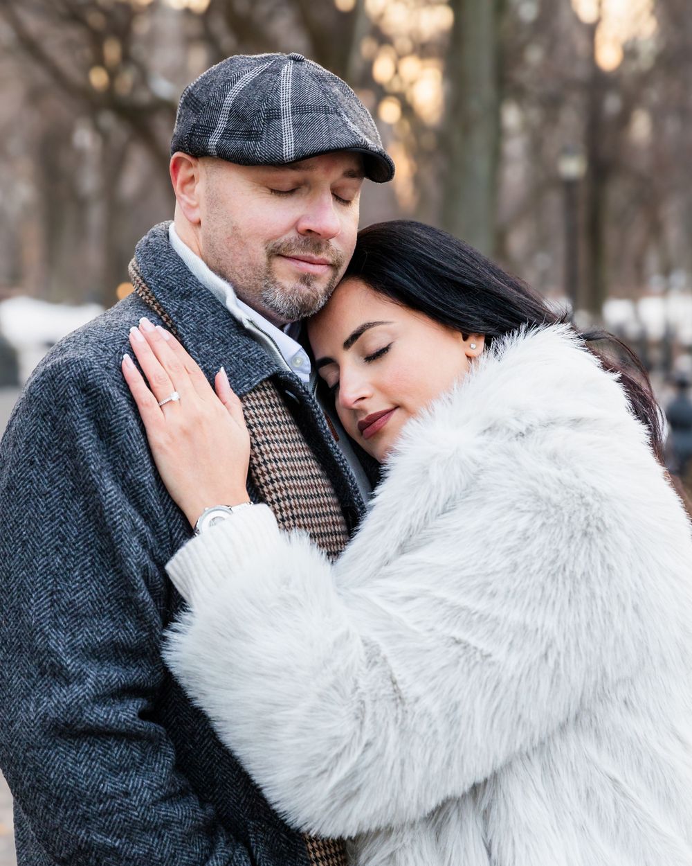 A tender embrace between a couple wearing winter coats and stylish accessories.