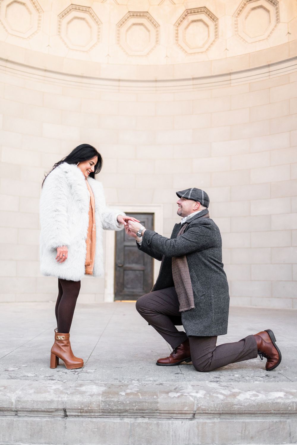 A romantic proposal moment captured in an architectural alcove with decorative ceiling details.