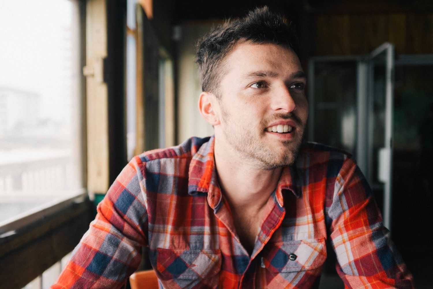 Person wearing plaid flannel shirt looking off to the side in contemplative pose.