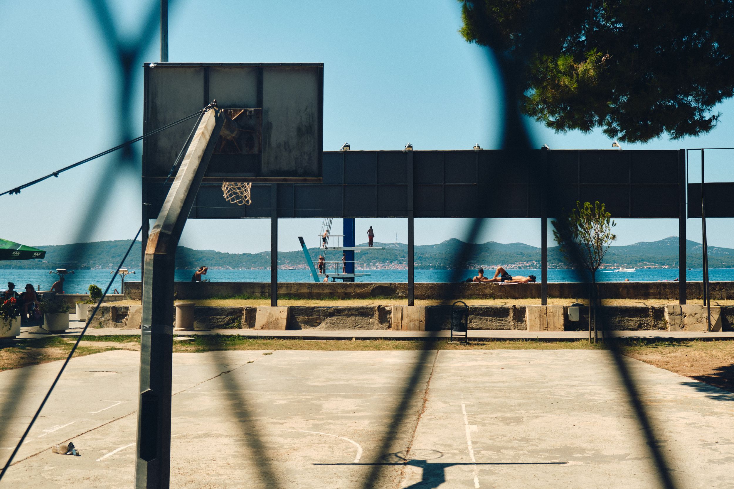 Basketball court by the sea with empty hoop and ocean view in the background.