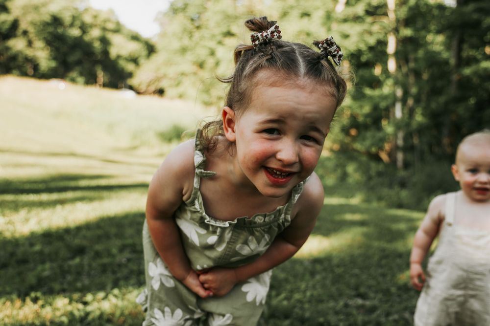 Children play and laugh together on grass during a summer day.
