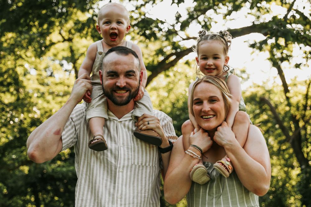 Happy family enjoying outdoor photography session in sunlit natural setting.