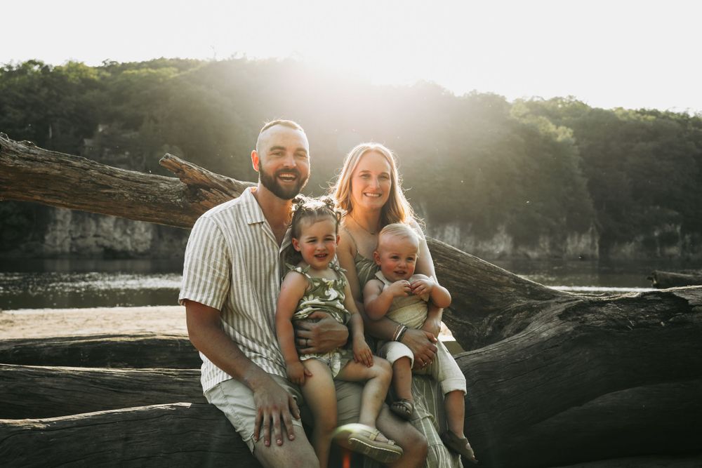 A family sits together on rocky terrain at sunset with cliffs visible in the background.