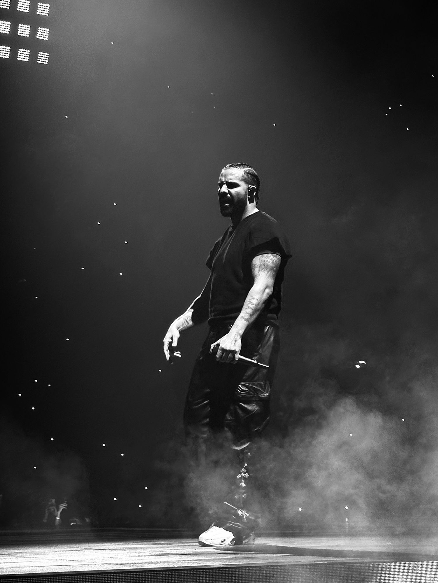 Artistic black and white performance photo with smoke effects and dramatic lighting.