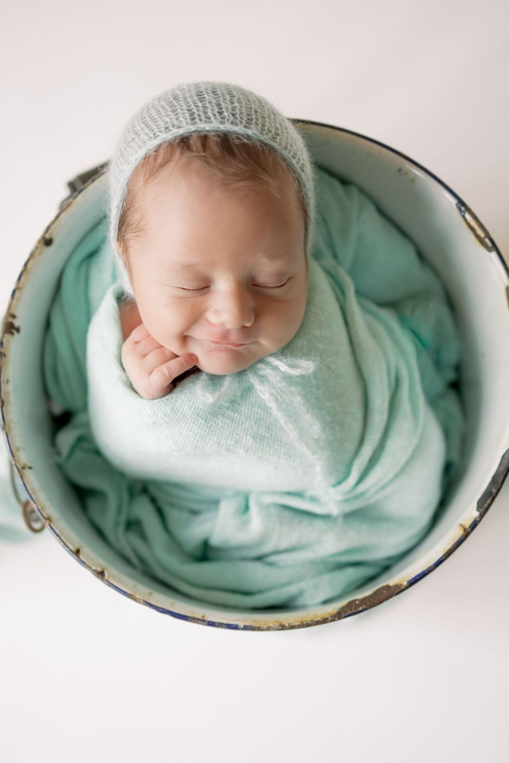 baby smiling in a bucket sleeping
