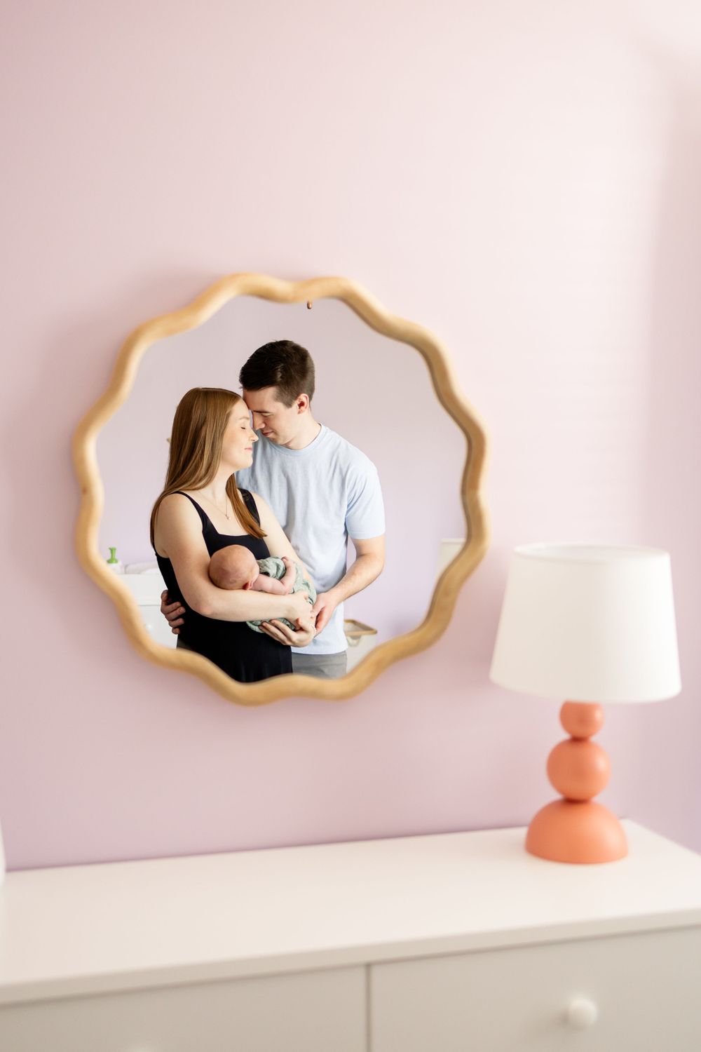 parents holding baby in mirror
