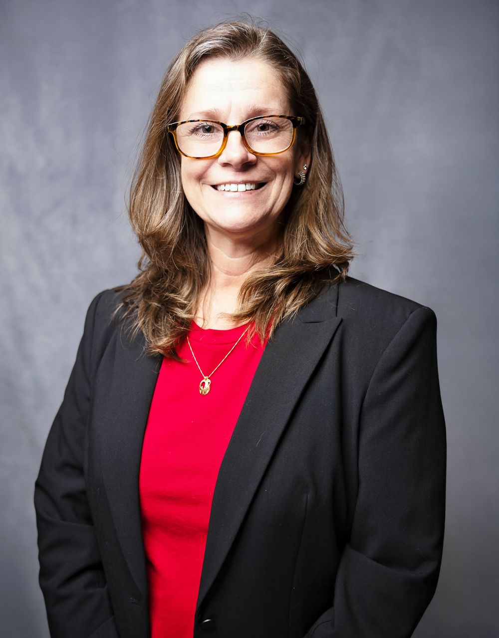 Professional headshots showing person in red top and black blazer against gray background.