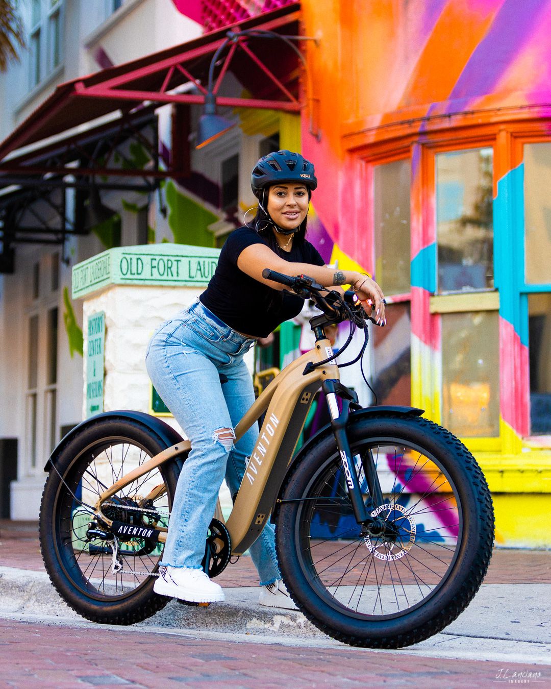 Electric fat tire bike parked in front of colorful wall with vibrant neon lighting.