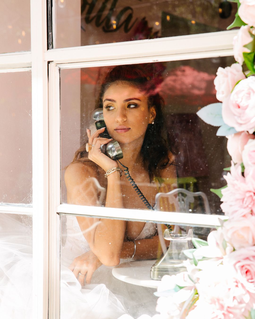 Window framed view with roses showing vintage telephone scene.
