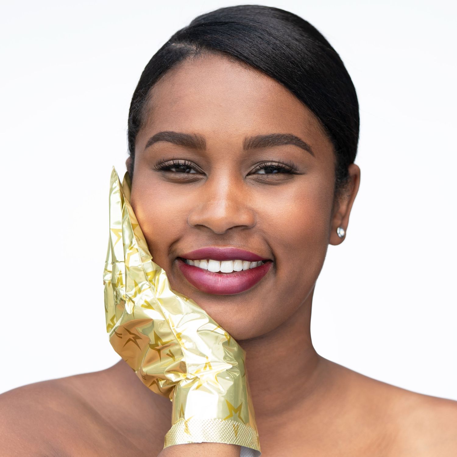 model met goudkleurige handschoenen aan van een beauty merk poseert voor witte achtergrond in daglicht studio in Eindhoven.