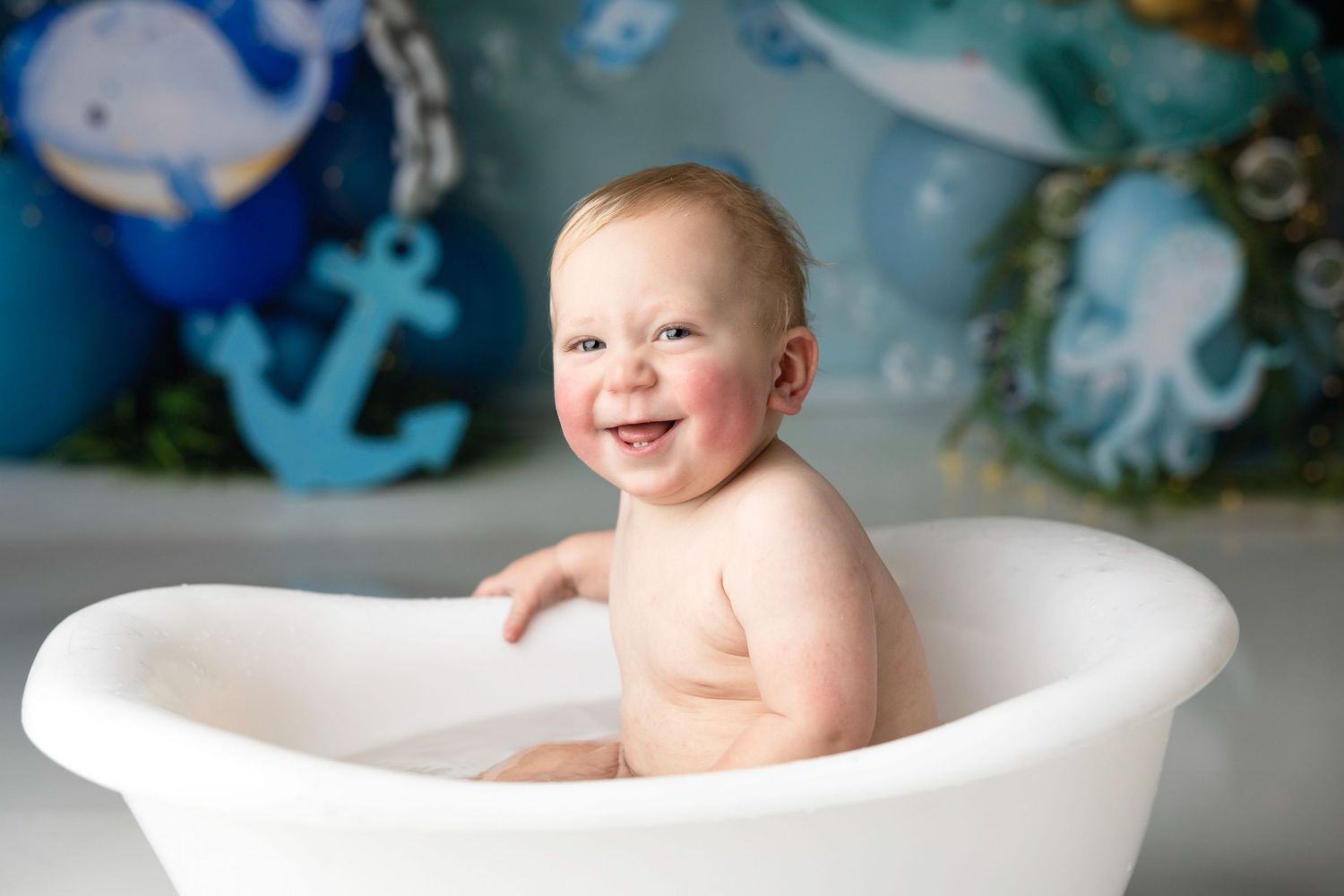 Nautical themed first birthday photoshoot with bubble decorations and bath setup.
