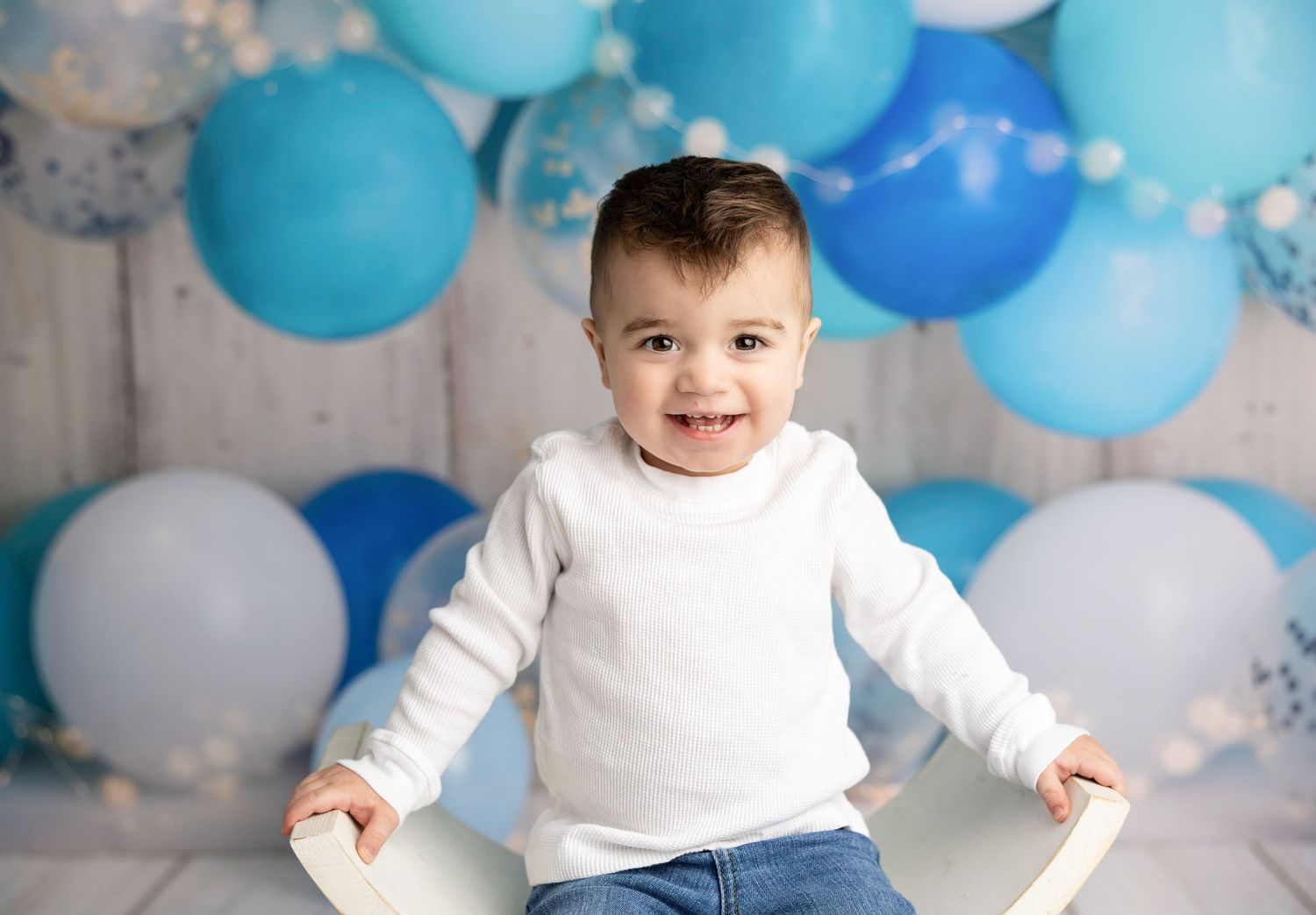 Birthday celebration setup with blue and white balloons against rustic wooden backdrop.