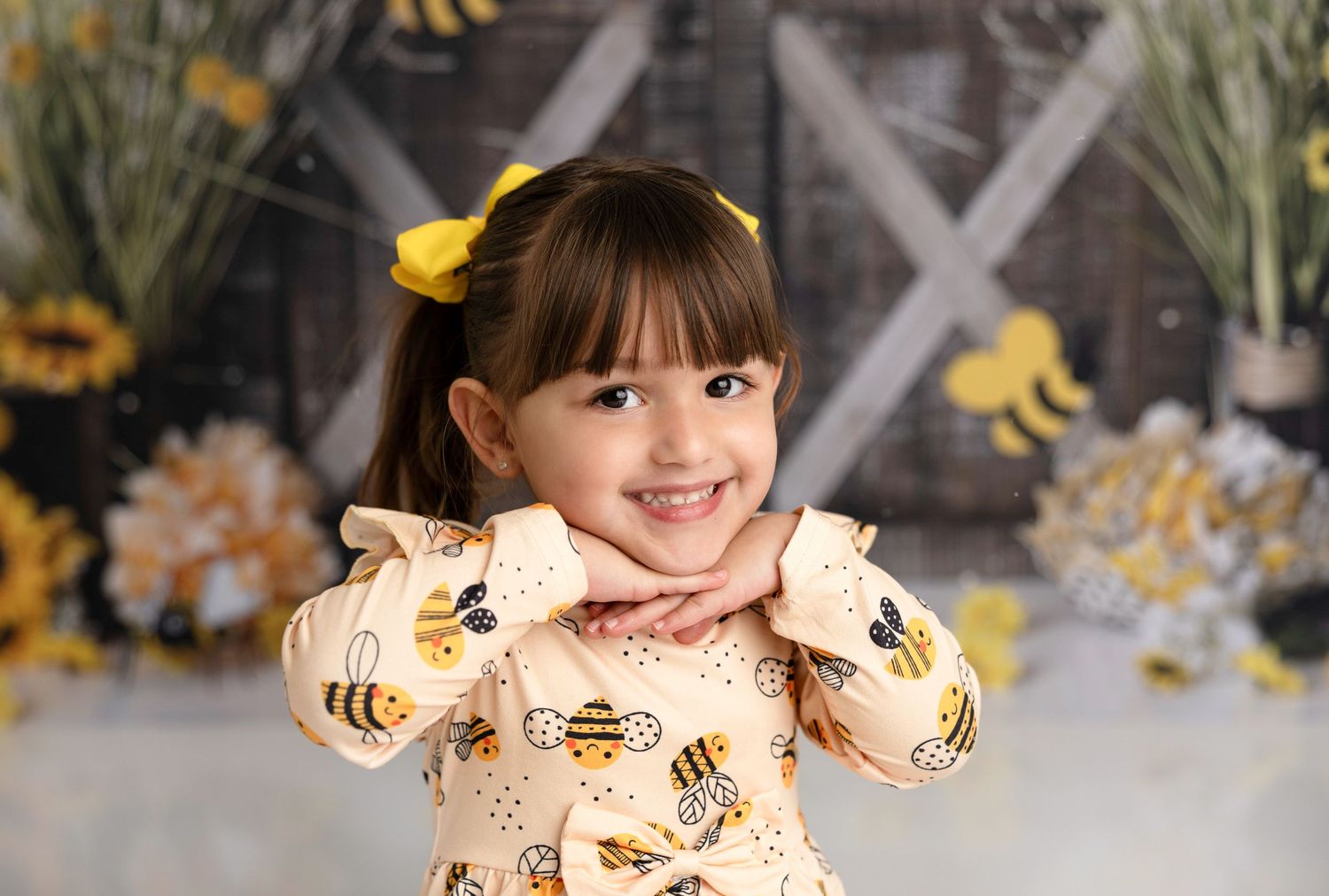 Portrait session against honeybee themed backdrop with yellow flowers and decorative elements.