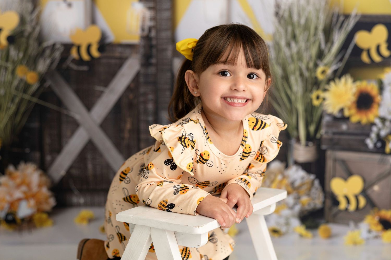 Child portrait session with bee-themed backdrop featuring yellow and black decorations.