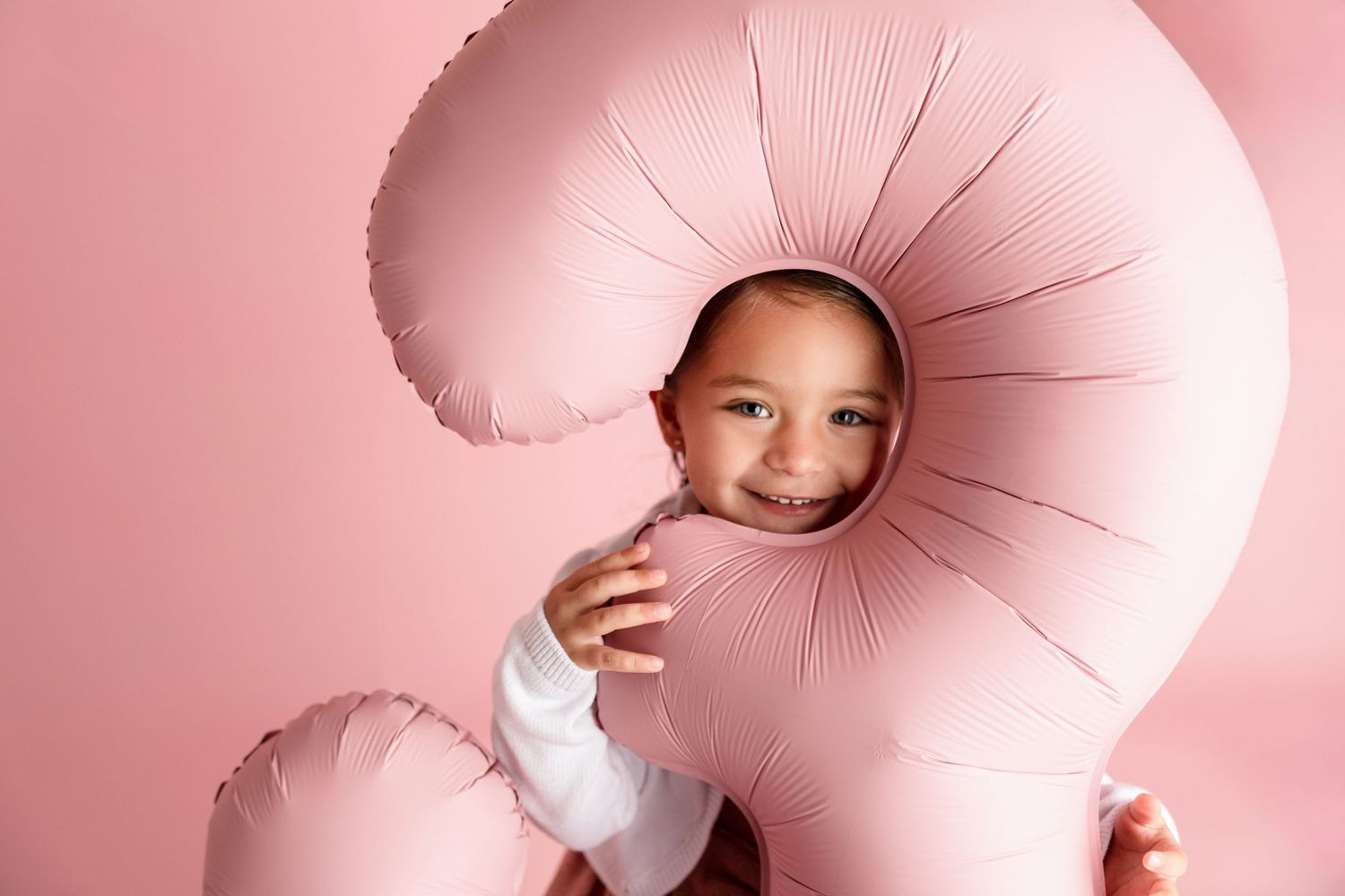 Creative portrait with pink spiral prop against pink background.