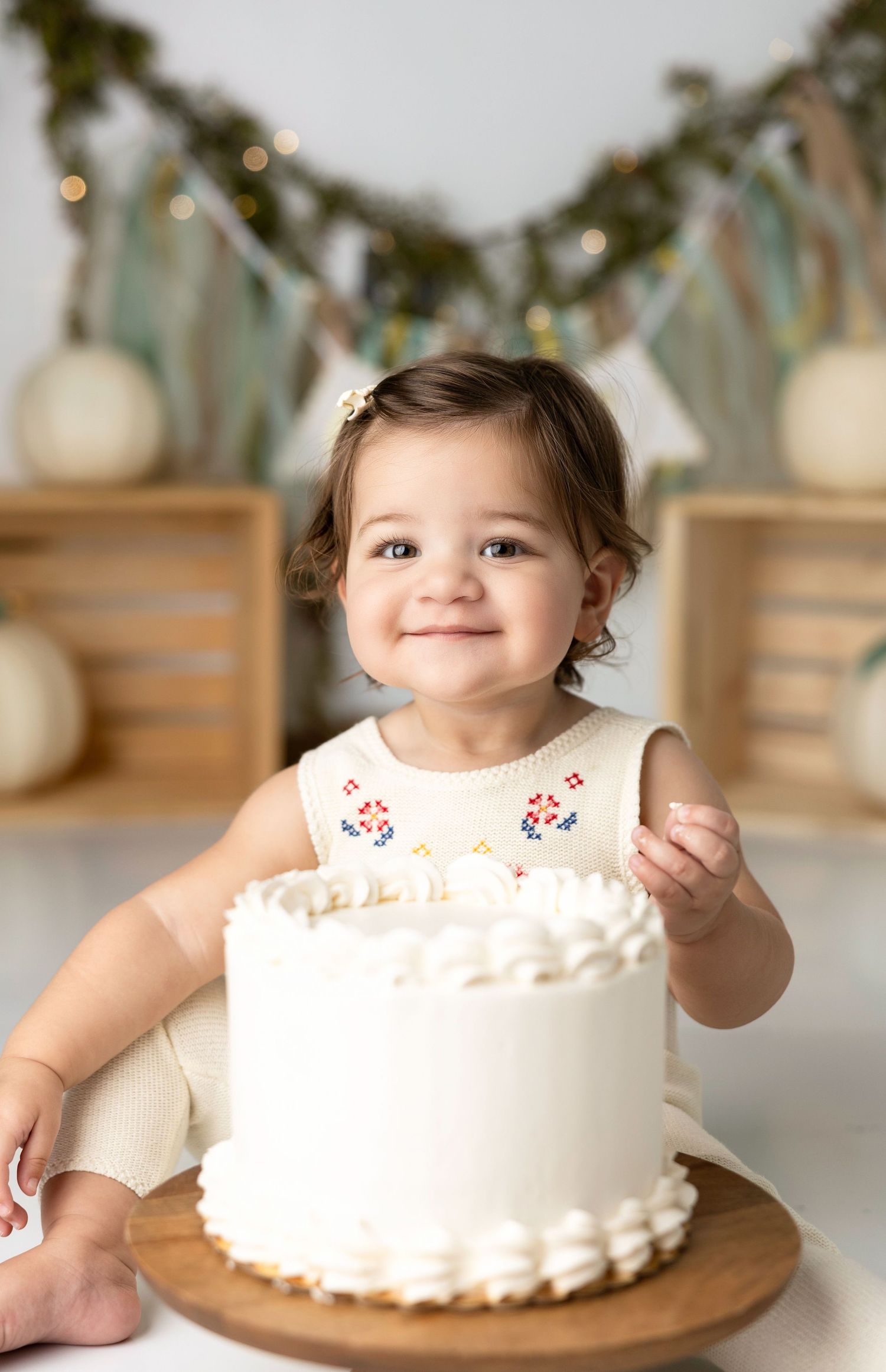 White birthday cake smash photo session with decorative background setup.