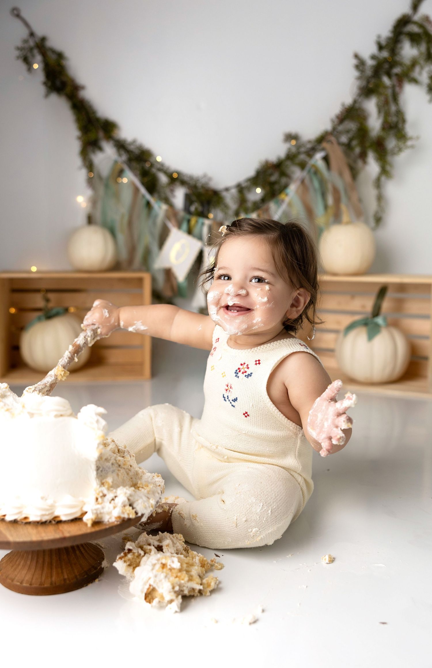 Cake smash photography session showing baby playing with white frosting.