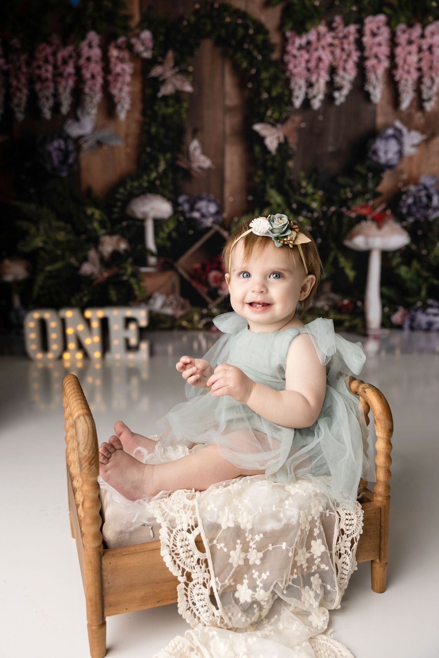 Baby's first birthday cake smash photoshoot with floral decorations and mint green tulle dress.