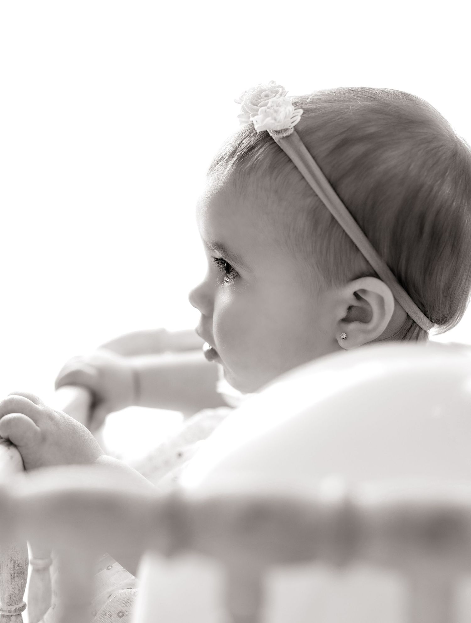 Black and white profile portrait of a baby wearing a delicate floral headband looking off to the side.