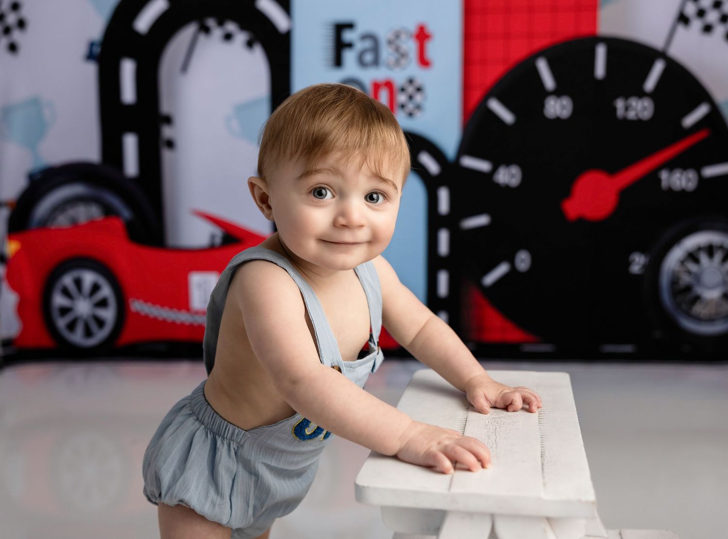 A child in a gray shirt sits at a table with a racing car themed background and wall decor.