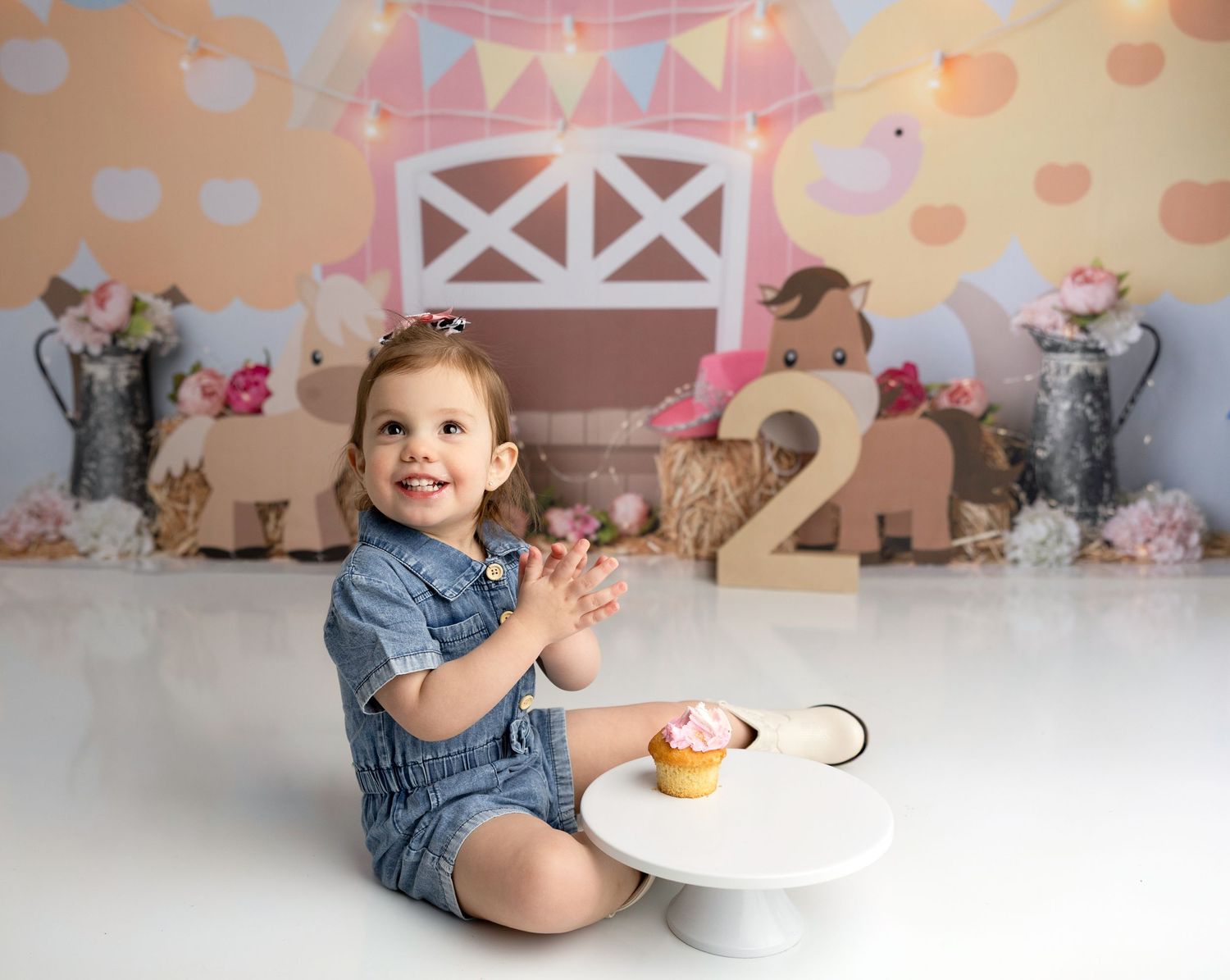 Baby in denim playing at festive party setup with pastel decorations.