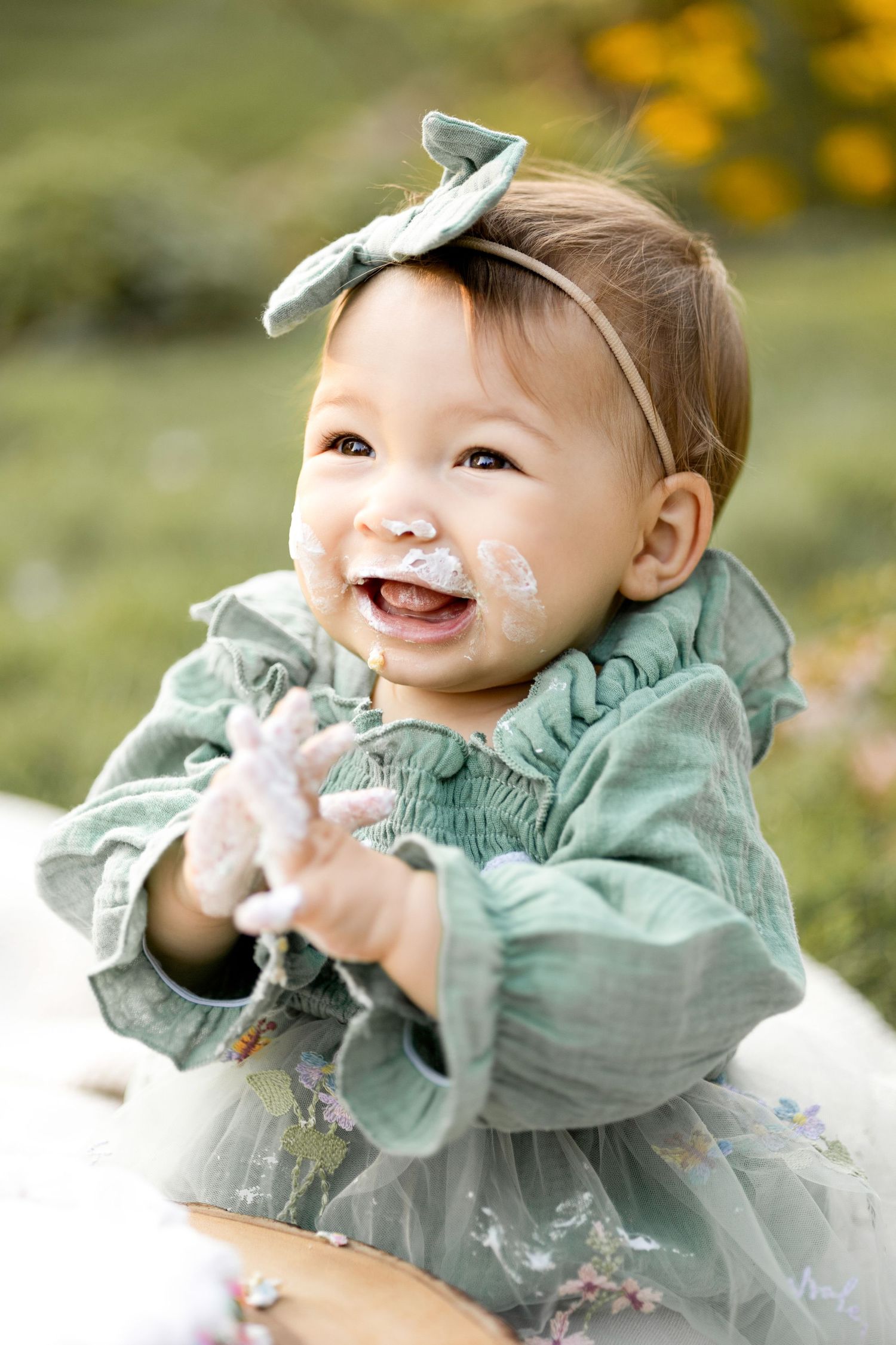 Baby in mint green dress laughing and playing on grass in a series of candid shots.