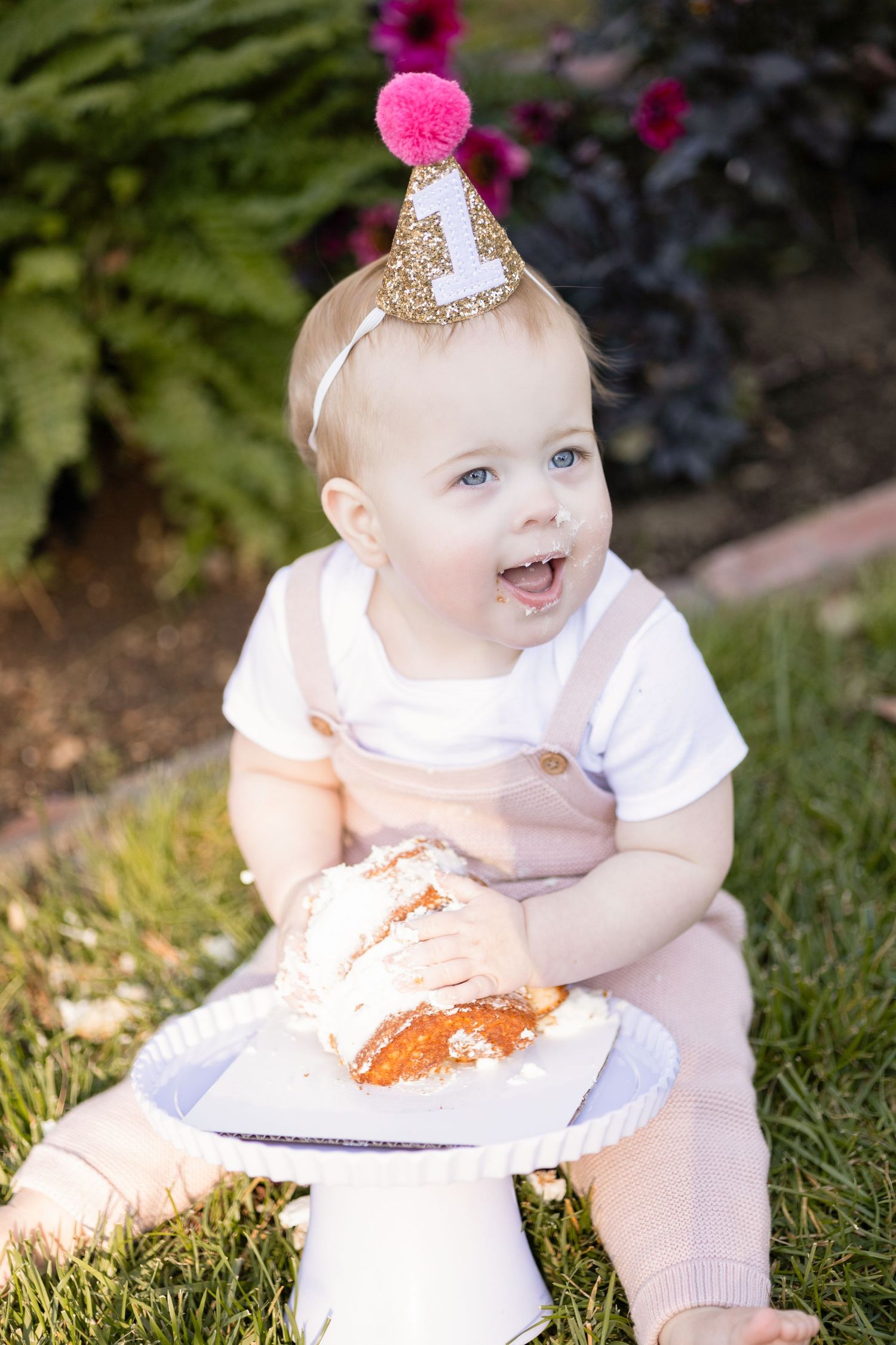 Baby's first birthday cake smash session outdoors with pink accessories.