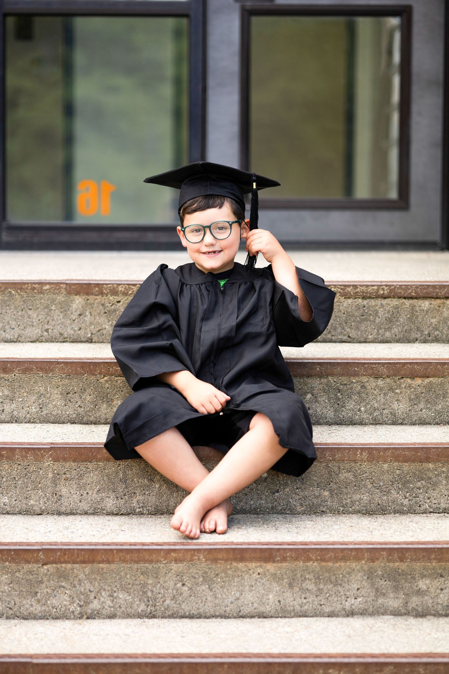 Graduate cap and gown photo series on concrete steps showing playful poses.