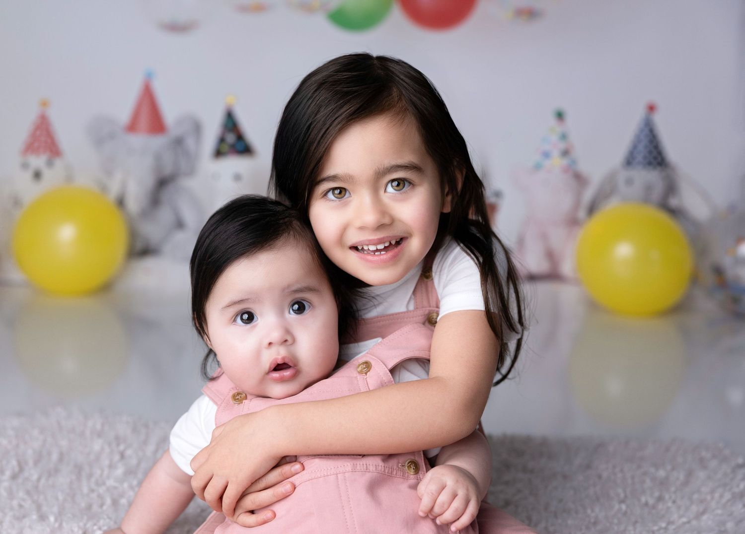 Two children pose together at birthday party with balloons and castle decorations in background.