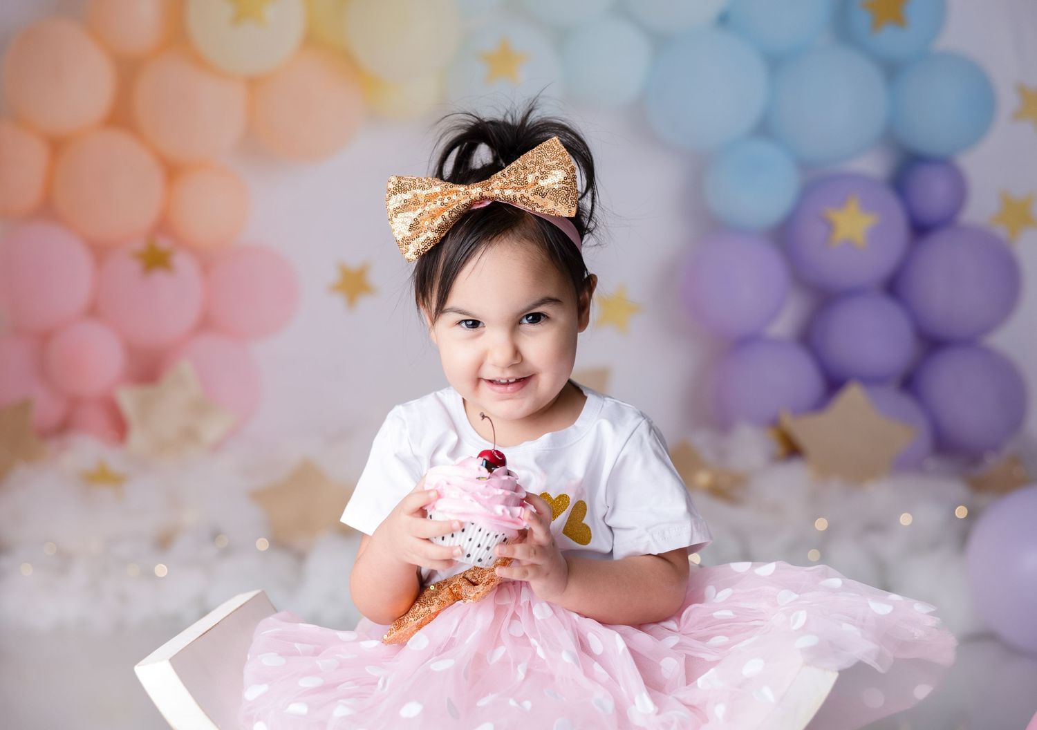 Birthday celebration setup with pastel balloon arch and decorative elements.