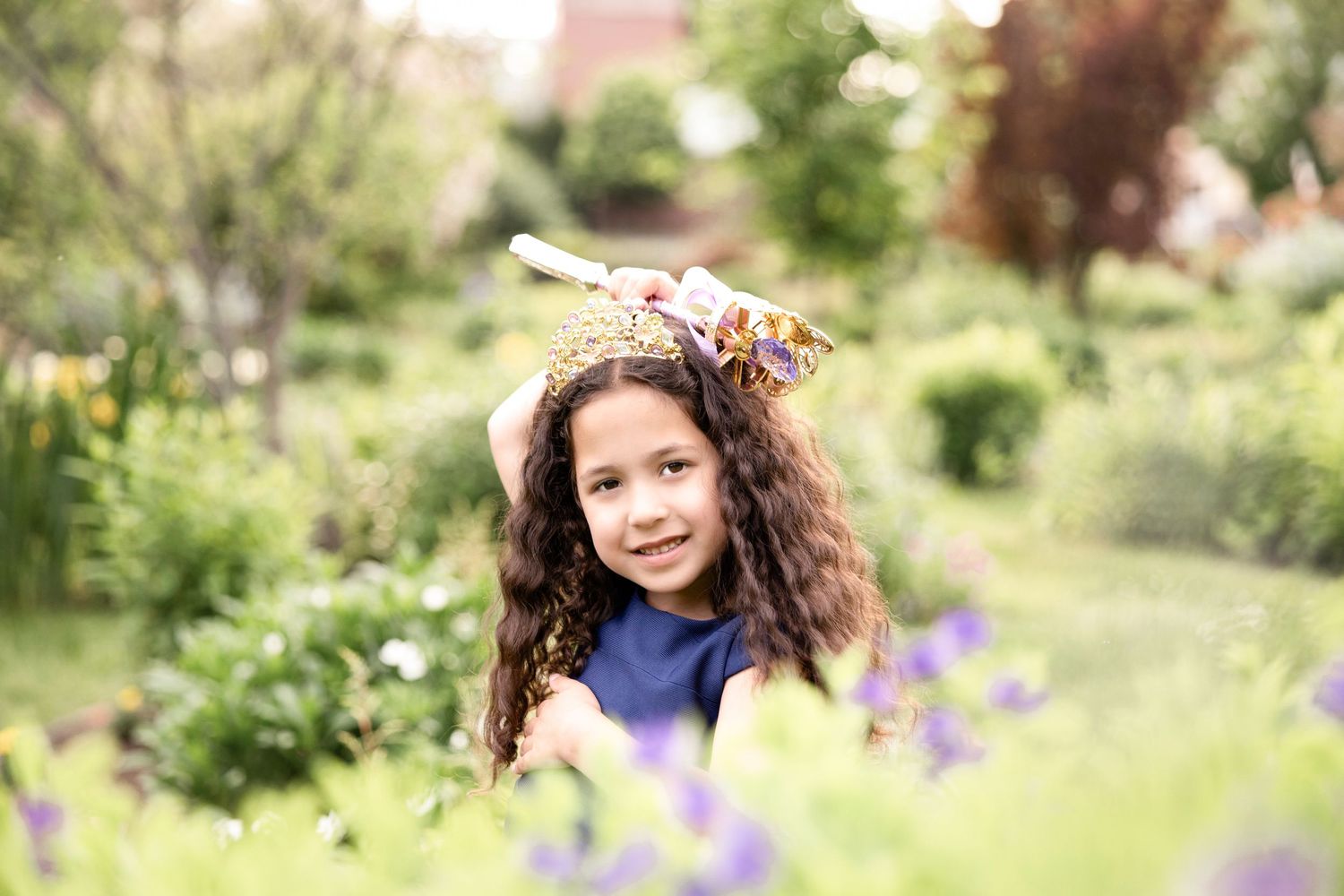 Young girl in navy dress playing outdoors in natural setting.