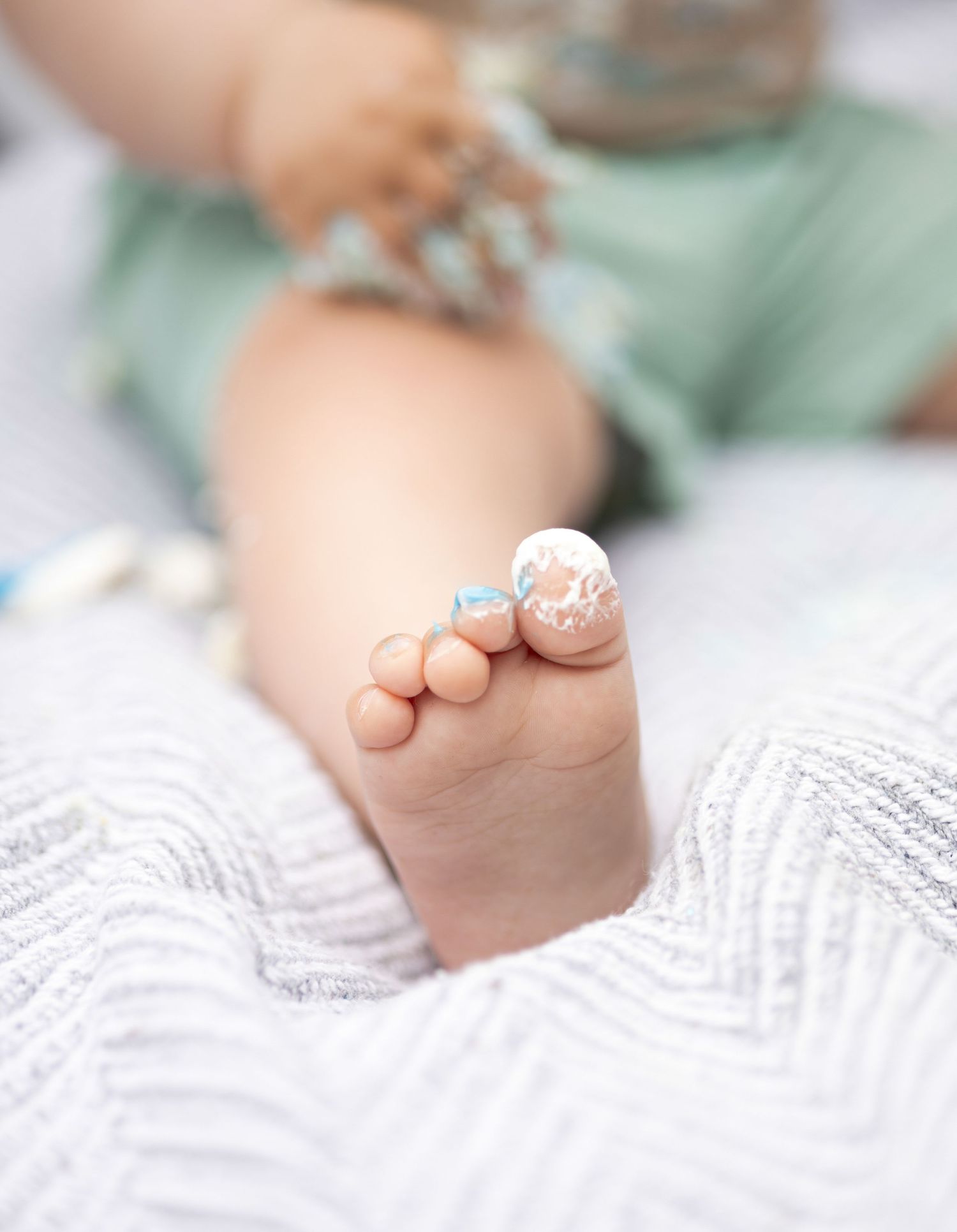 Close up of tiny baby feet with sparkly decorations on white textured fabric.