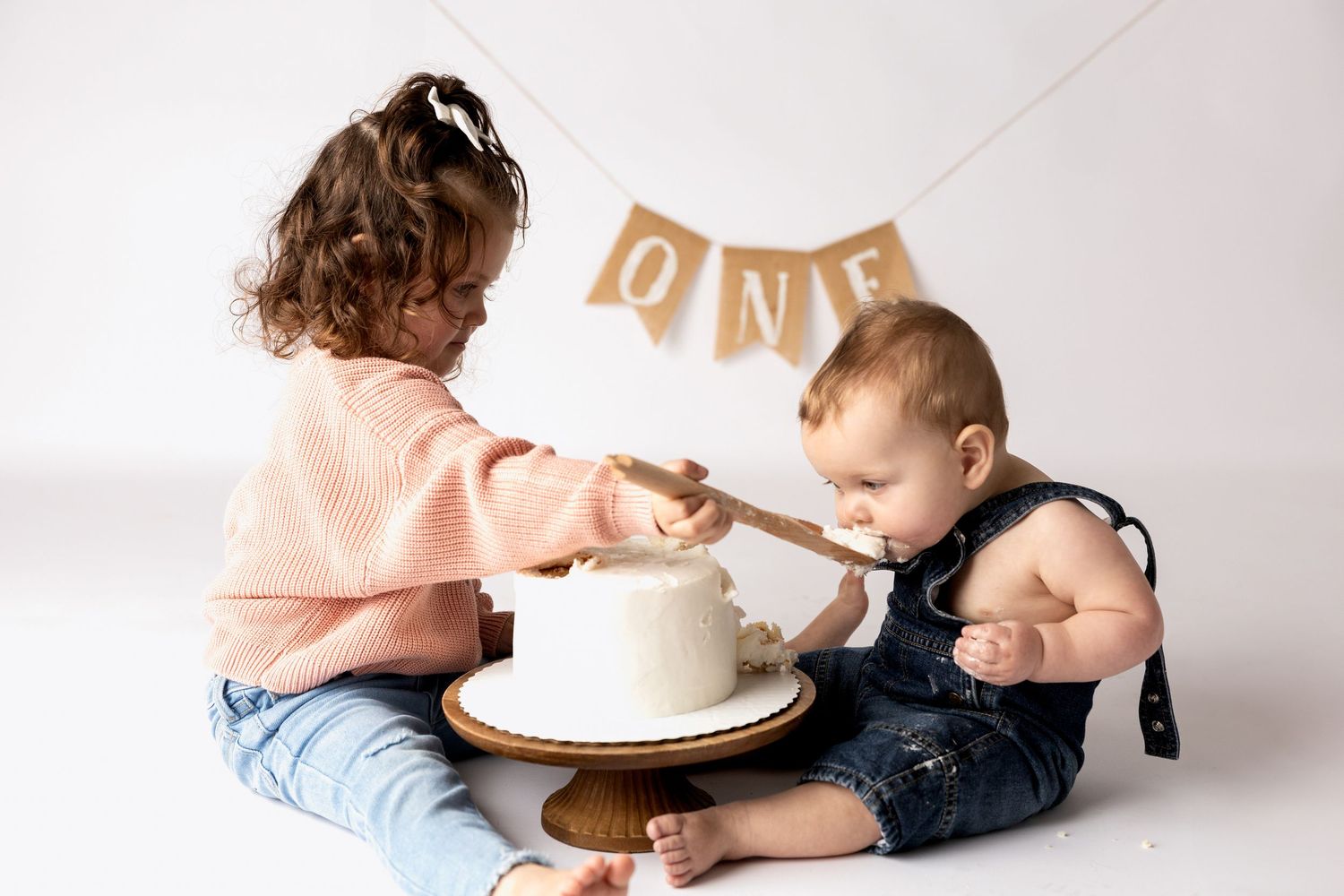 First birthday cake smash photo session on white background with gold banner.