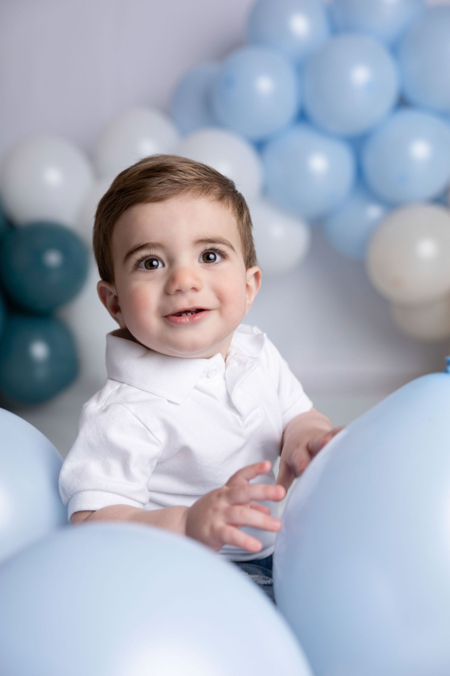 Baby photoshoot with light blue and white balloon backdrop.