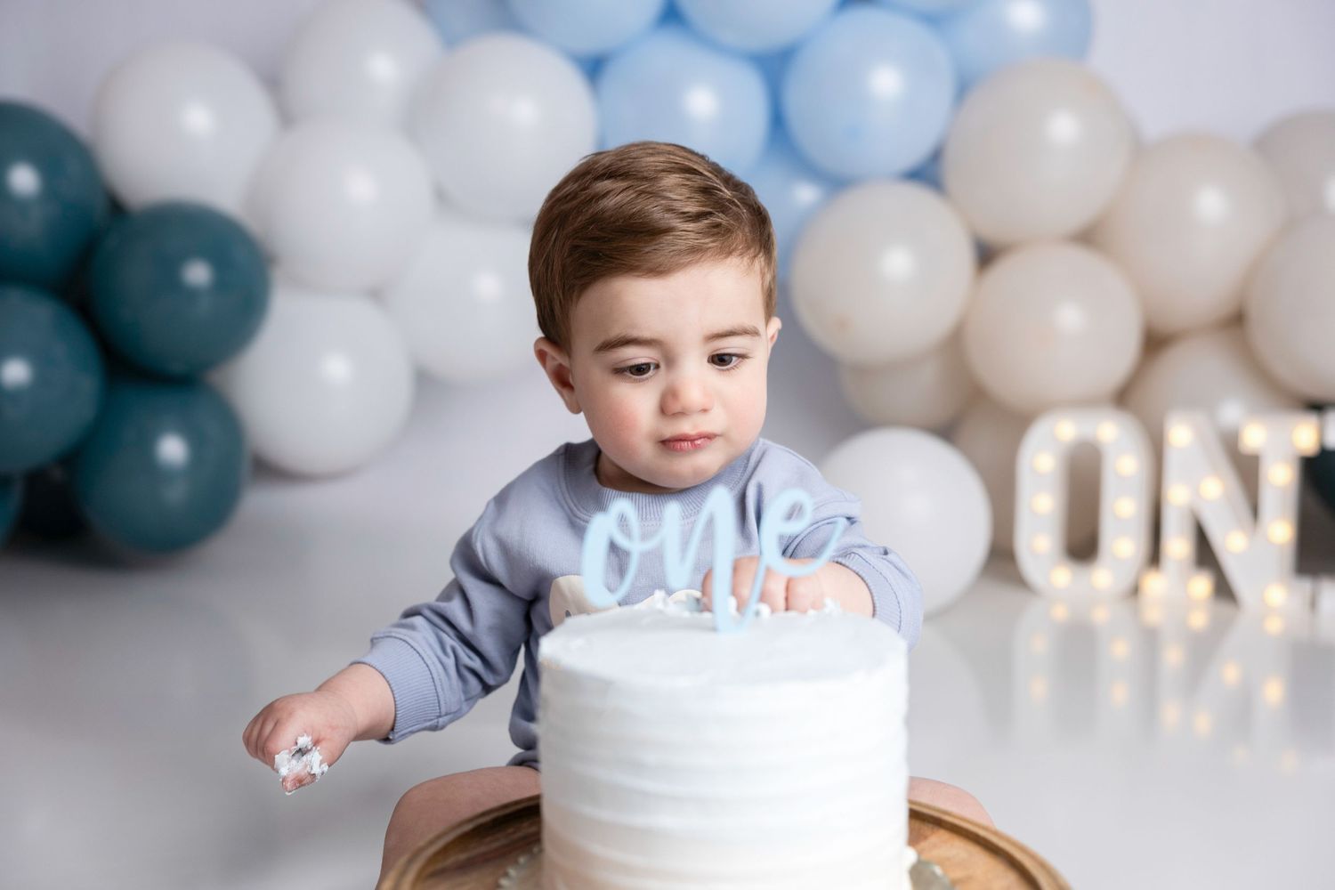 Baby's cake smash photography session with blue and white balloon decorations.