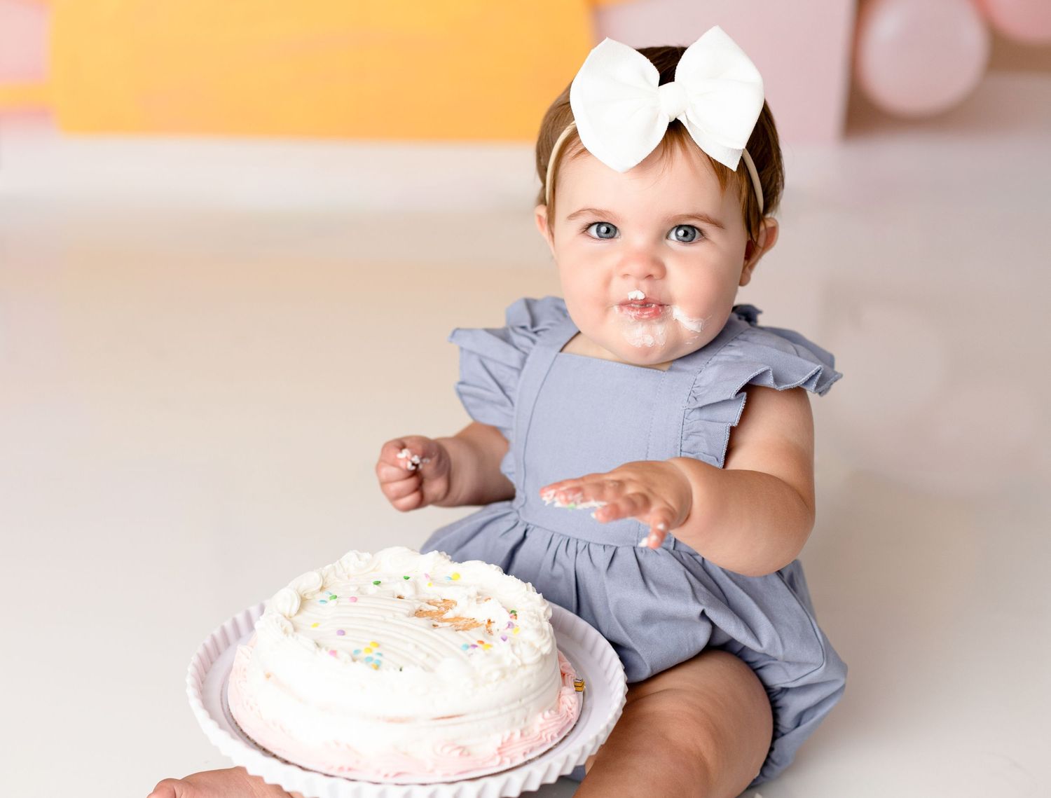 Baby's first birthday cake smash session with pink frosted cake.