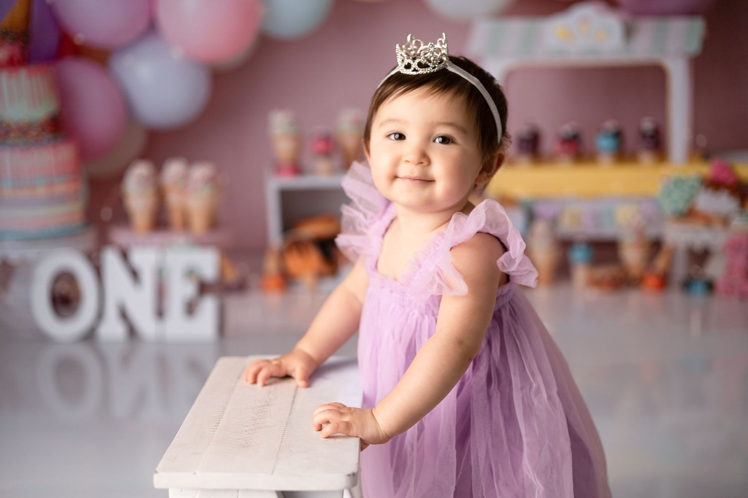 Birthday celebration setup with pink and pastel balloons and decorations against a soft pink background.
