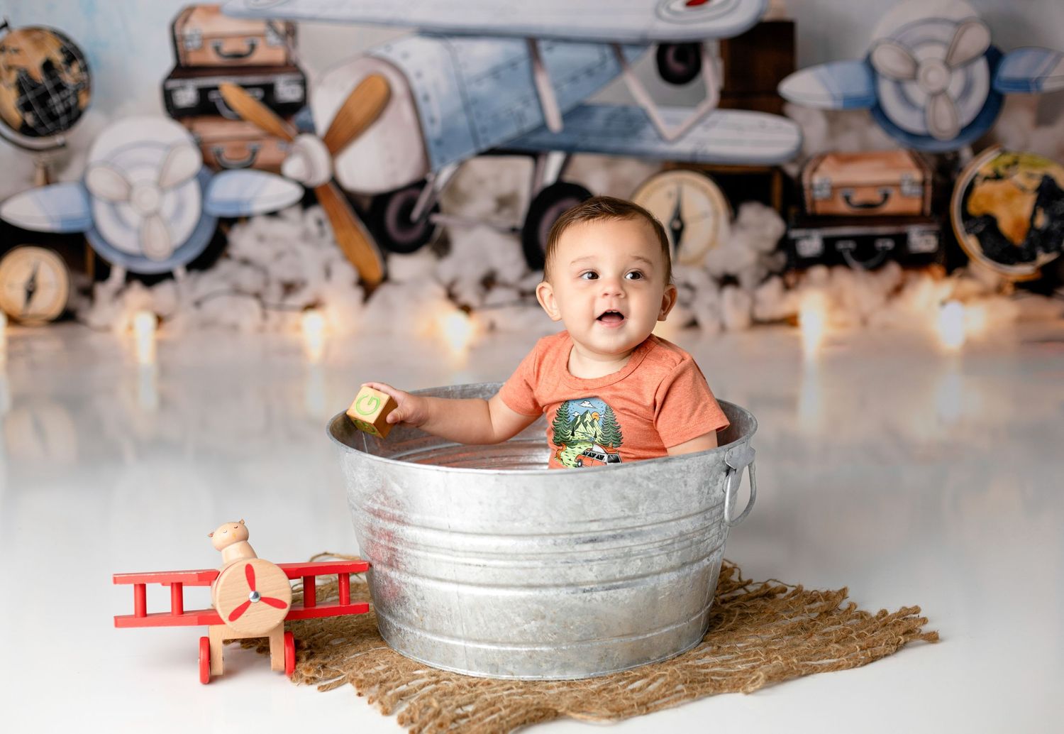 Baby bath setup with metal tub and decorative elements against blue background.