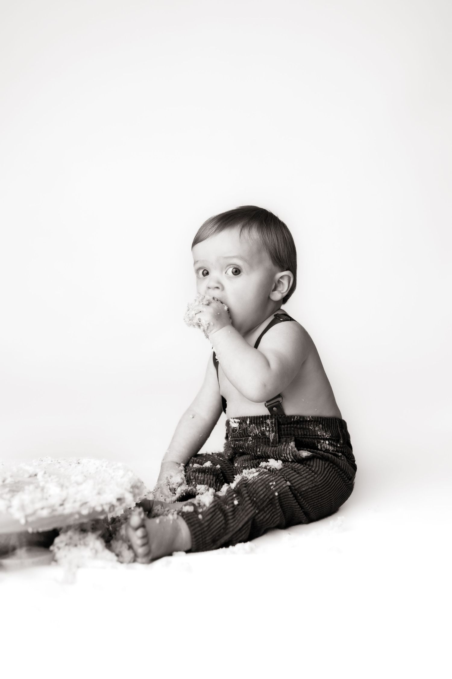 Artistic black and white photo series showing a cake smash session with white backdrop.