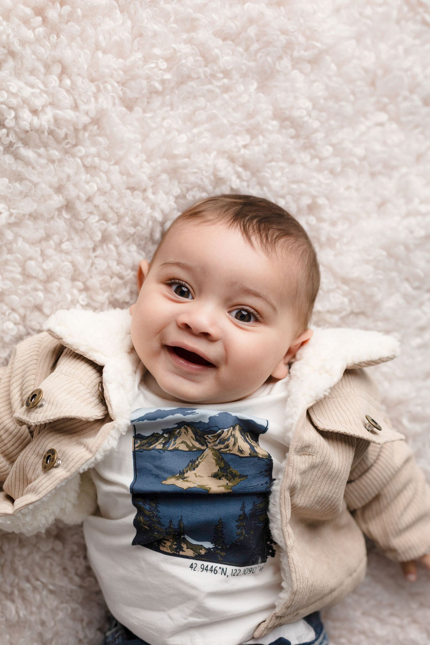 Baby portrait on plush white rug wearing winter themed outfit.