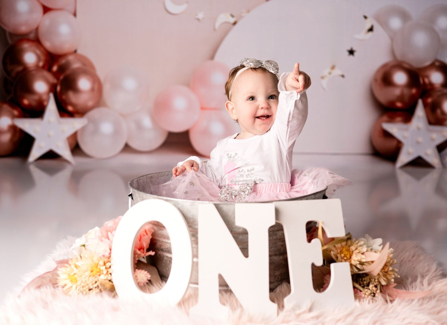 First birthday setup with rose gold balloons and ONE letters in pink theme.