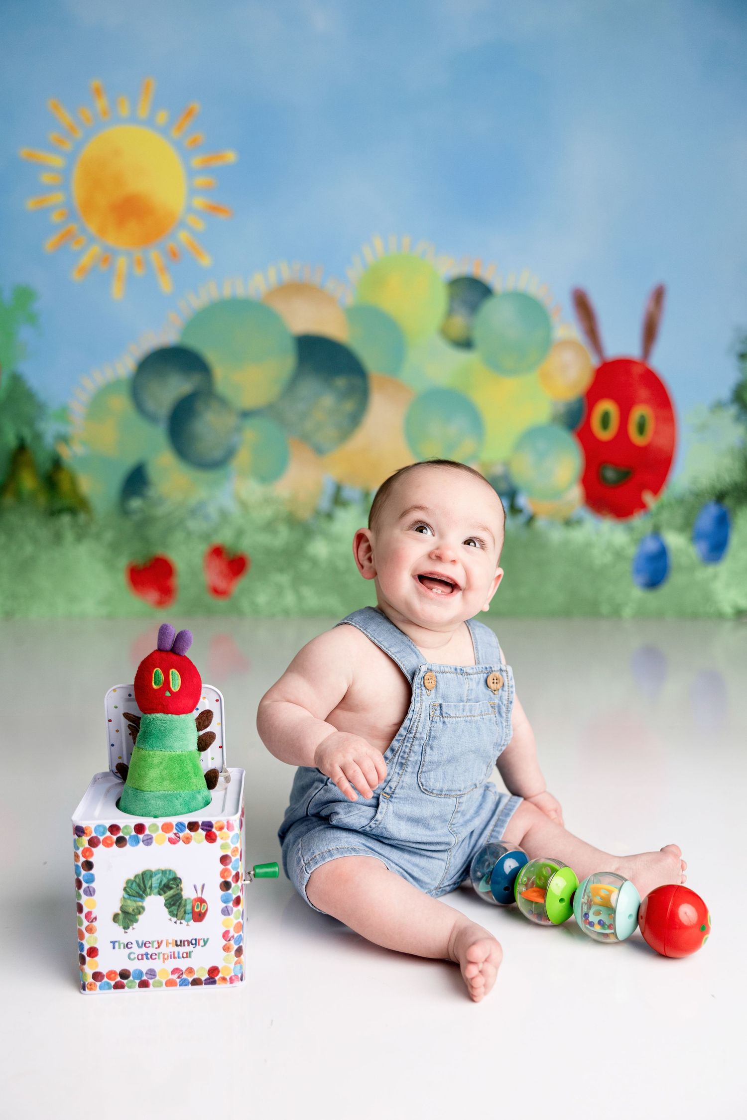 Colorful nursery photo setup with whimsical painted background, toys, and props for milestone photography.