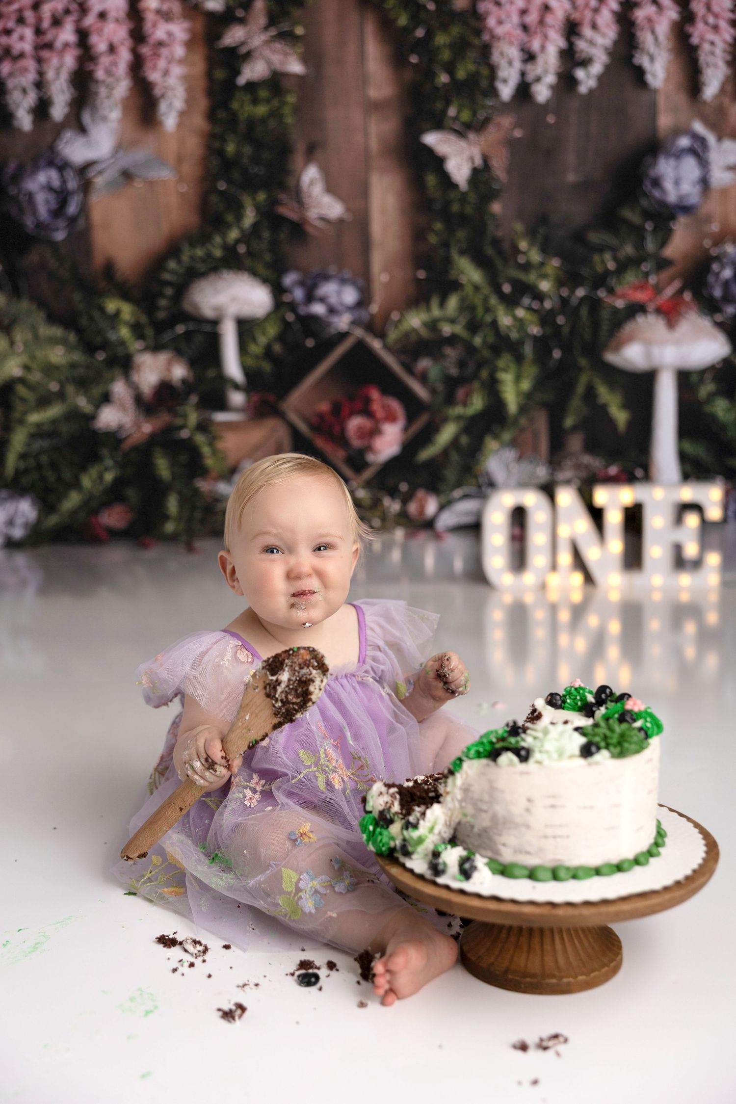A cake smash photo session showing a baby making a mess with birthday cake.