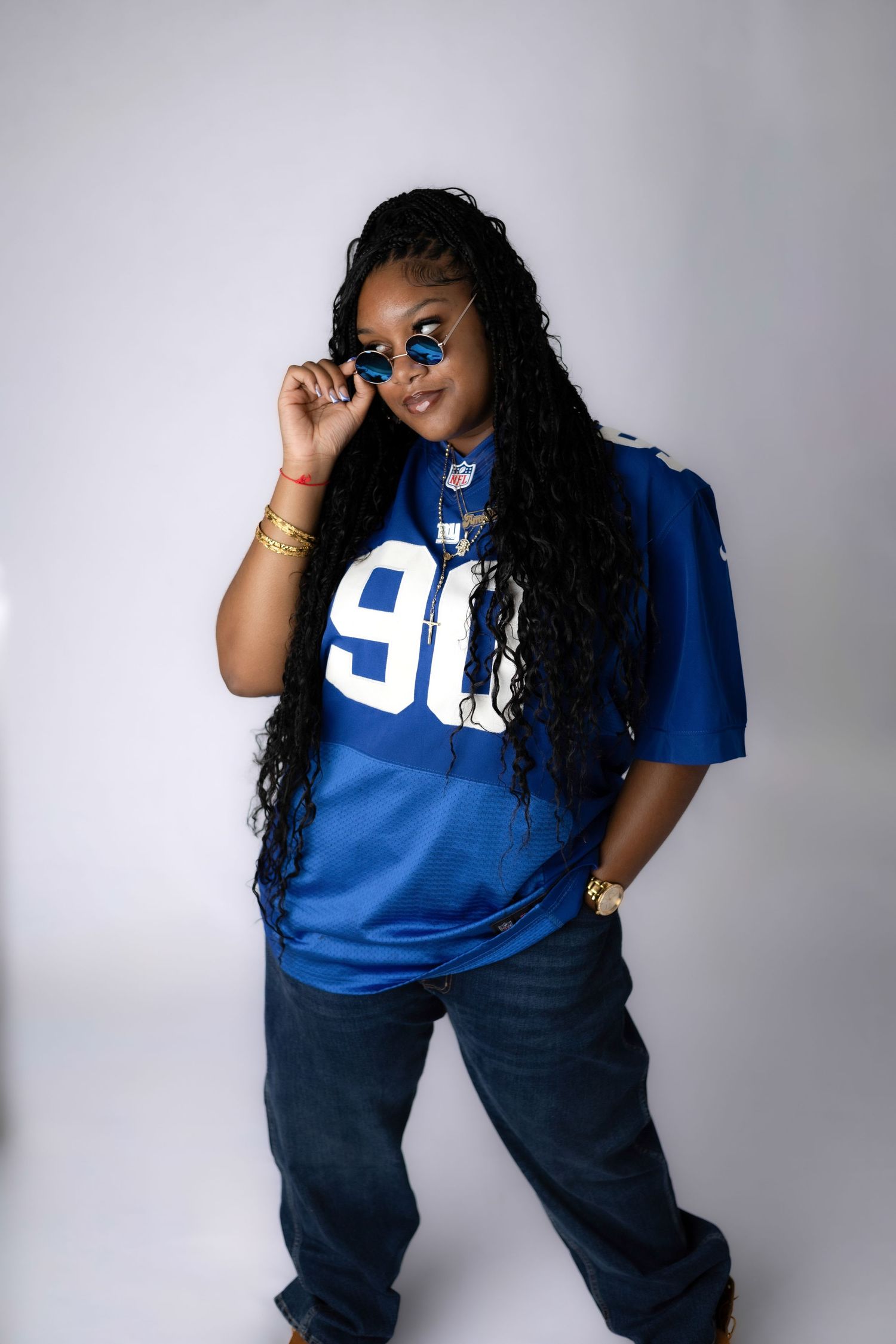 Model wearing NFL jersey and jeans poses confidently in studio setting.