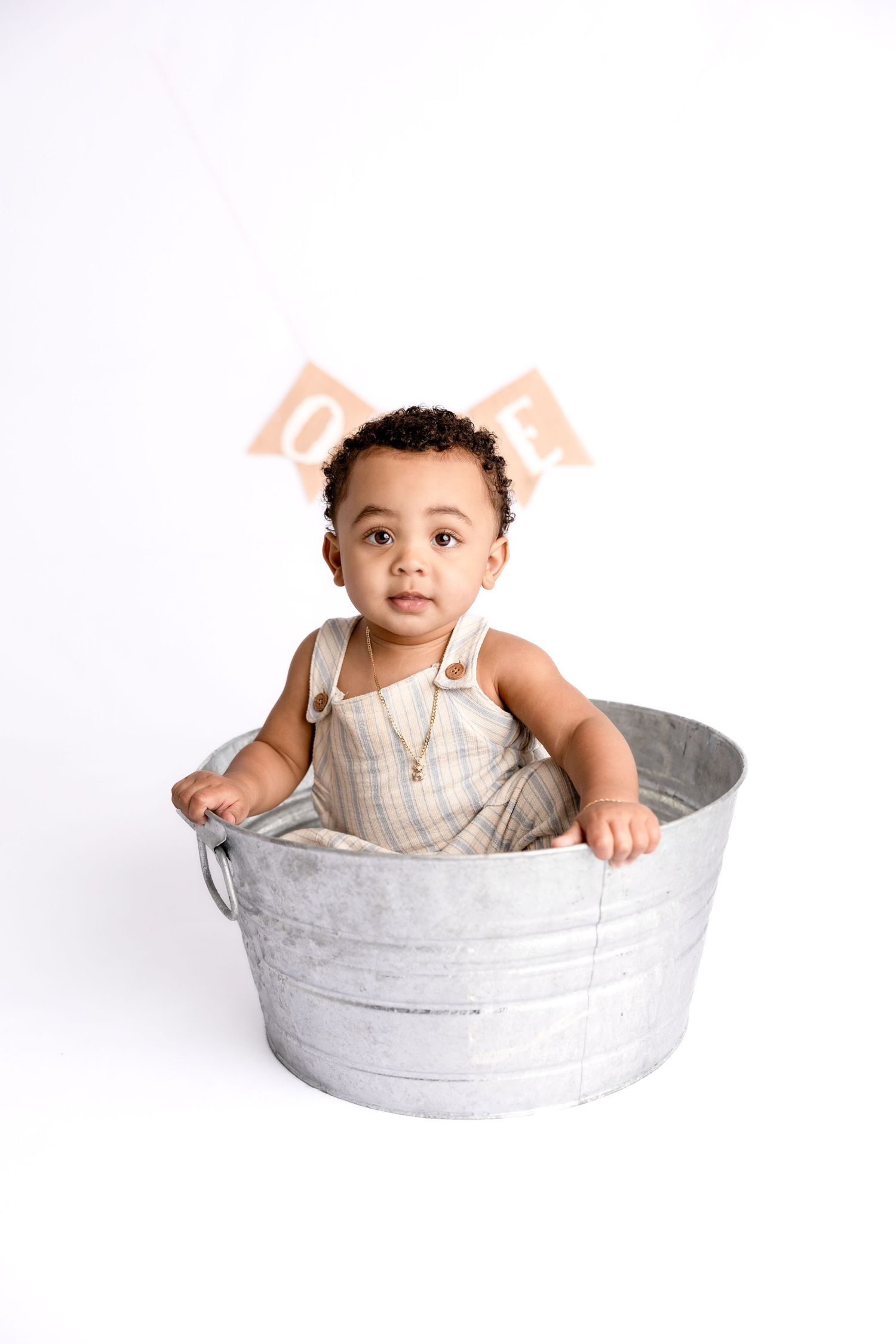 Baby milestone photos in galvanized metal tub against white background.