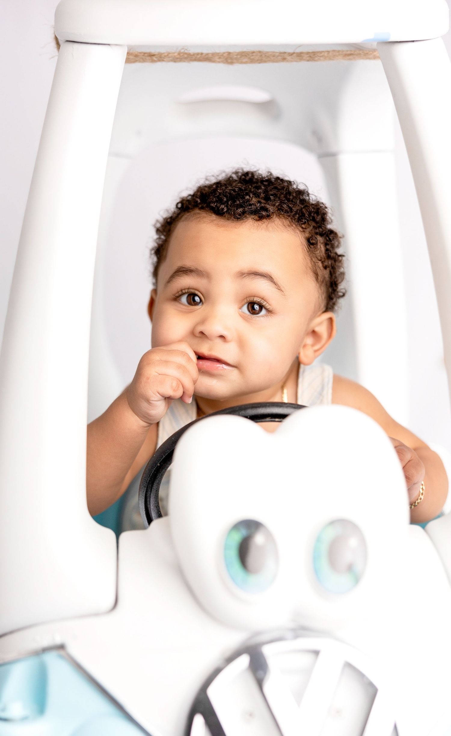 Creative baby photography with white number one prop against clean backdrop.